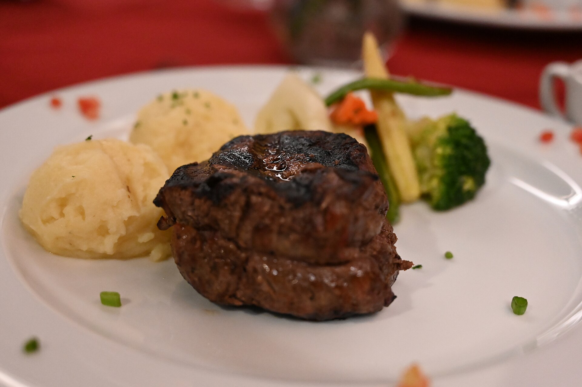 Seared fillet steak with mashed potatoes, broccoli and green beans on a white plate