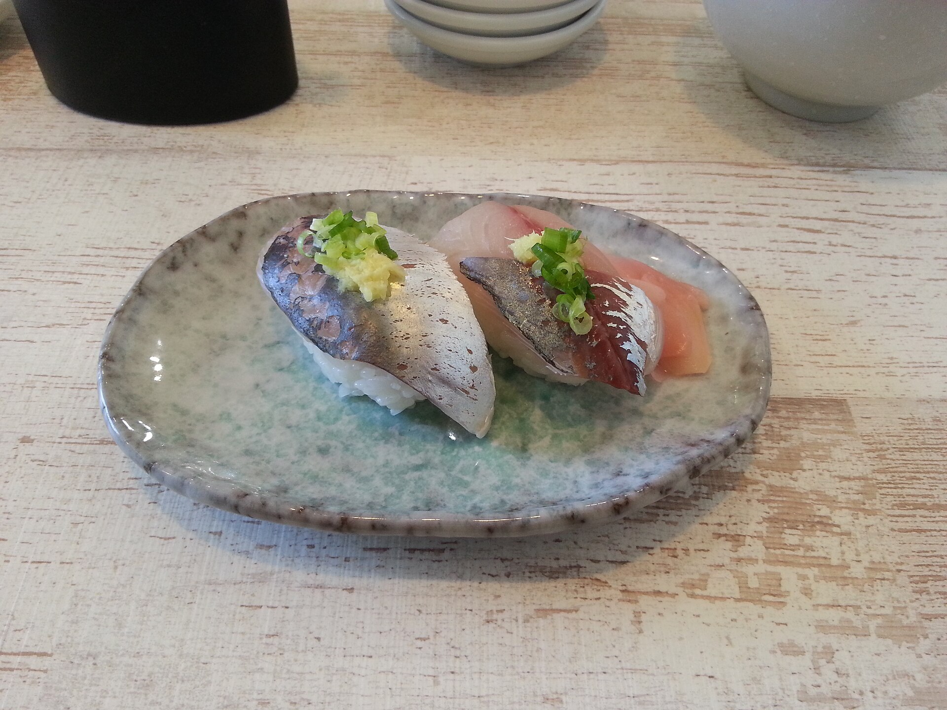 Two pieces of nigiri on a small ceramic dish