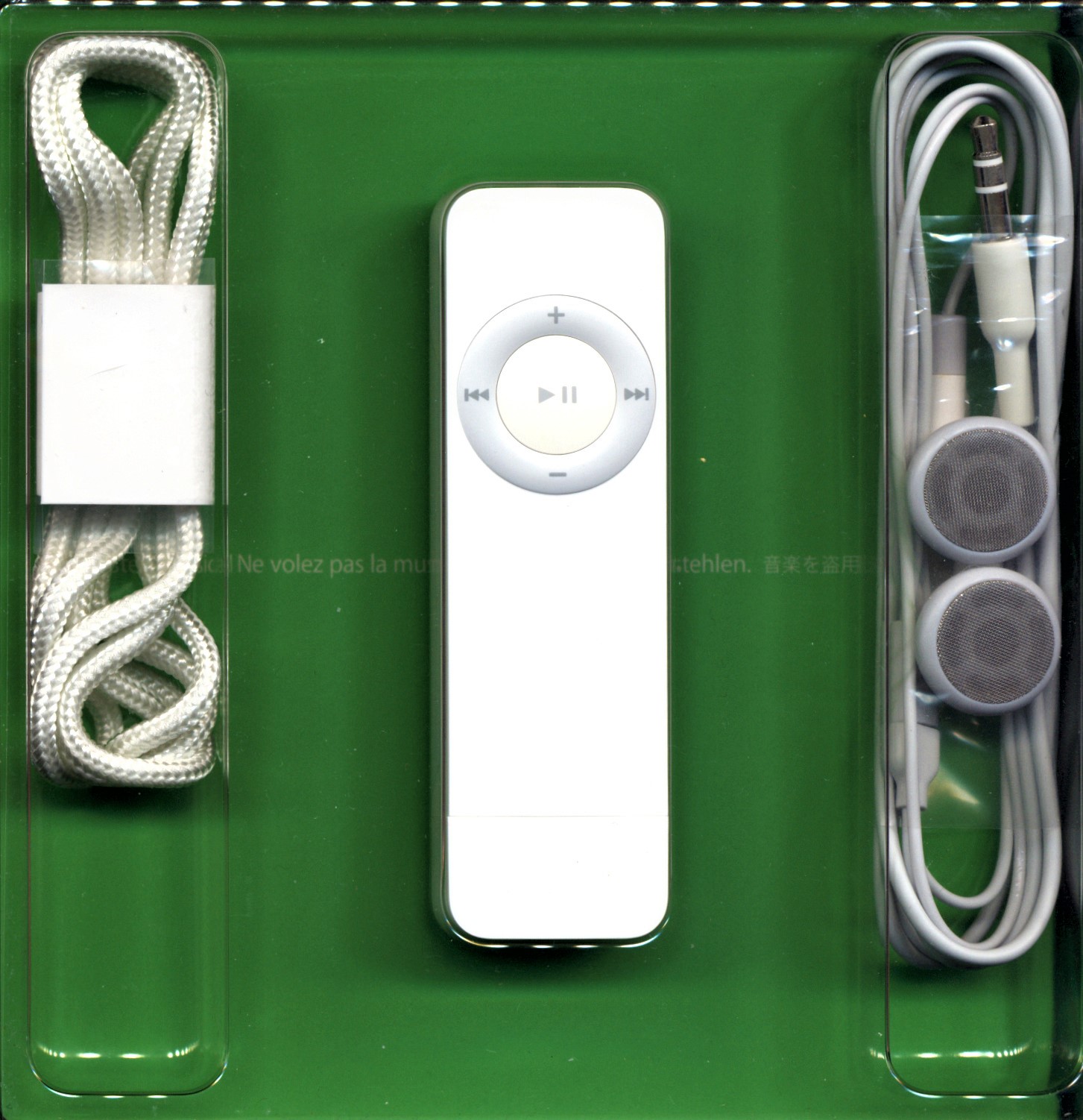 A first-generation iPod shuffle in its box with lanyard and earbuds